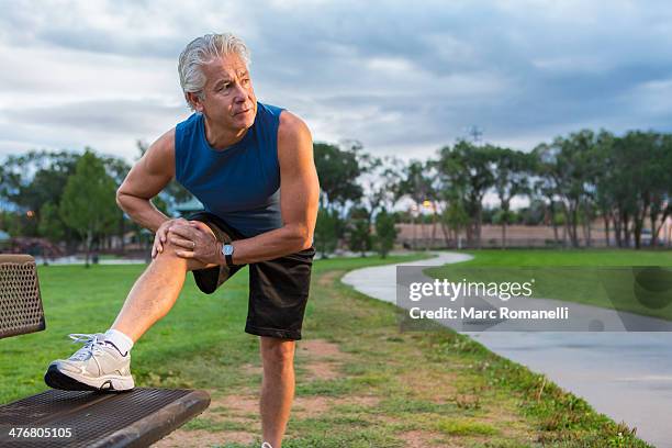 hispanic man stretching in park - latina legs stockfoto's en -beelden
