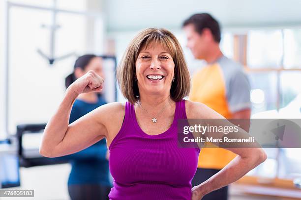 caucasian woman flexing her muscles in gym - alleen seniore vrouwen stockfoto's en -beelden