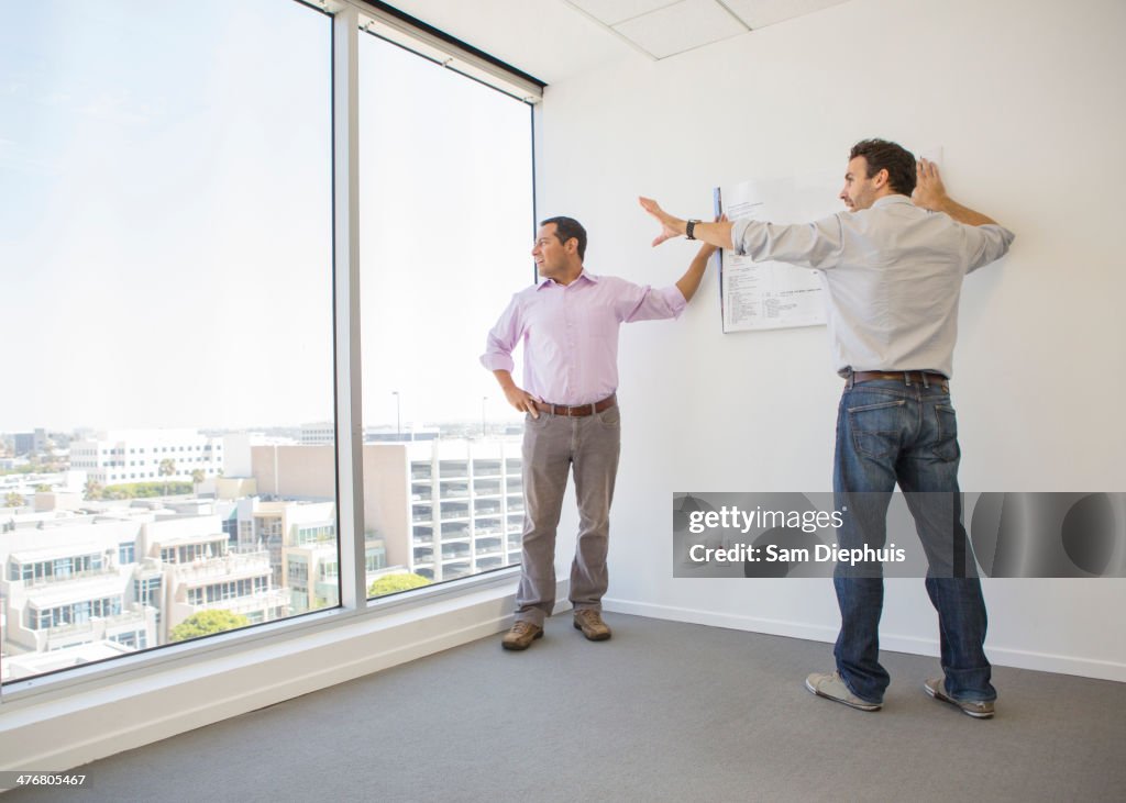 Hispanic businessmen examining blueprints in office