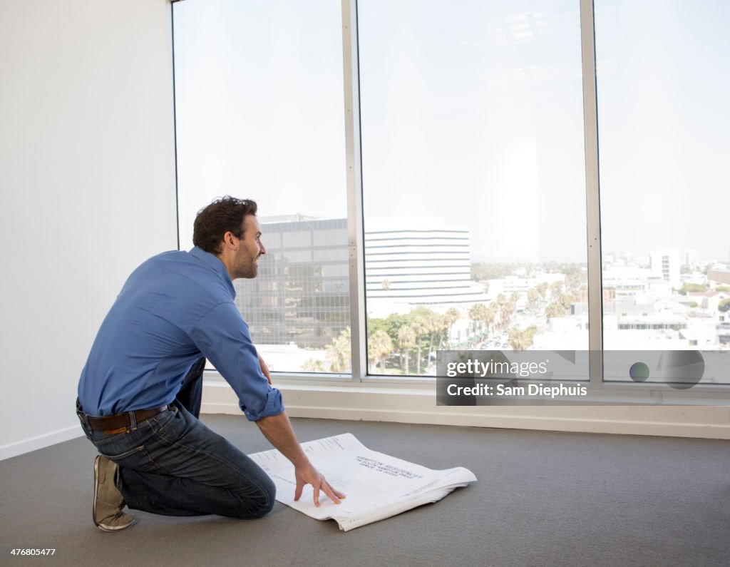 Hispanic businessman examining blueprints in office