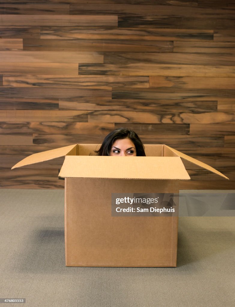 Mixed race woman hiding in cardboard box