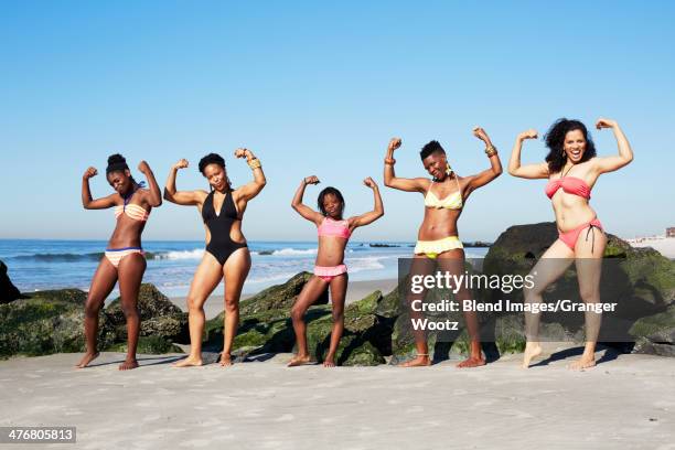 women flexing muscles on beach - silly girl foto e immagini stock