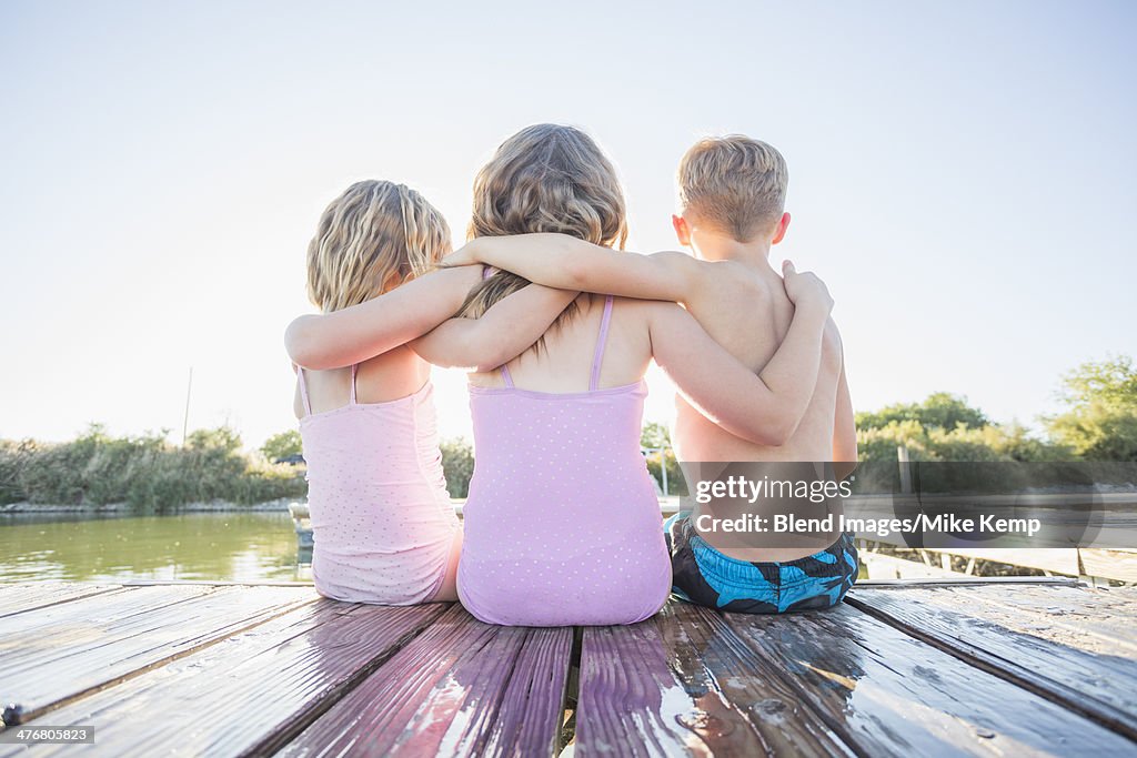 Caucasian children sitting on dock