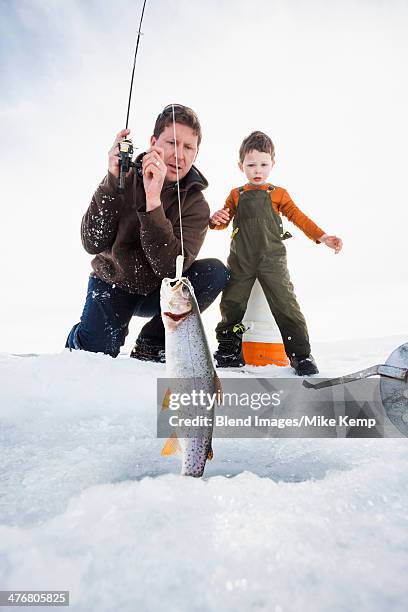 caucasian father and son ice fishing - ice fishing stock pictures, royalty-free photos & images