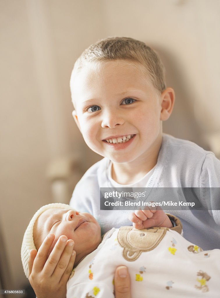 Caucasian boy holding newborn baby brother