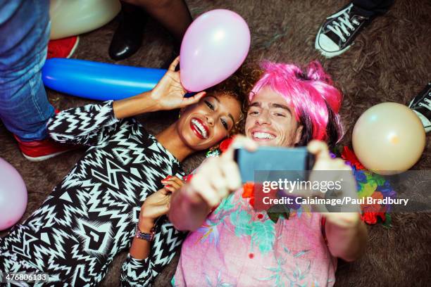 Couple taking self-portrait with cell phone on floor at party