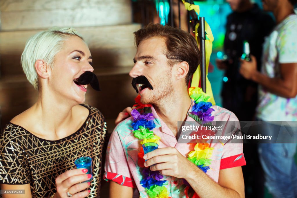 Couple wearing fake mustaches at party