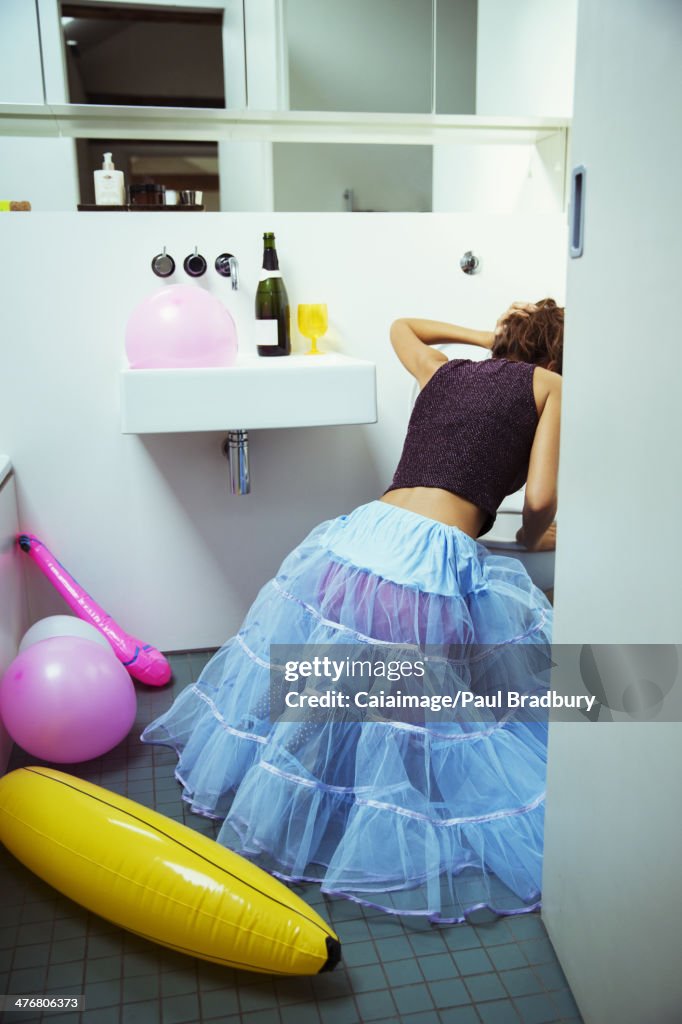 Woman vomiting into toilet at party