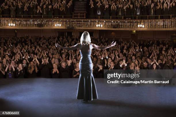 Performer standing with arms outstretched on stage in theater