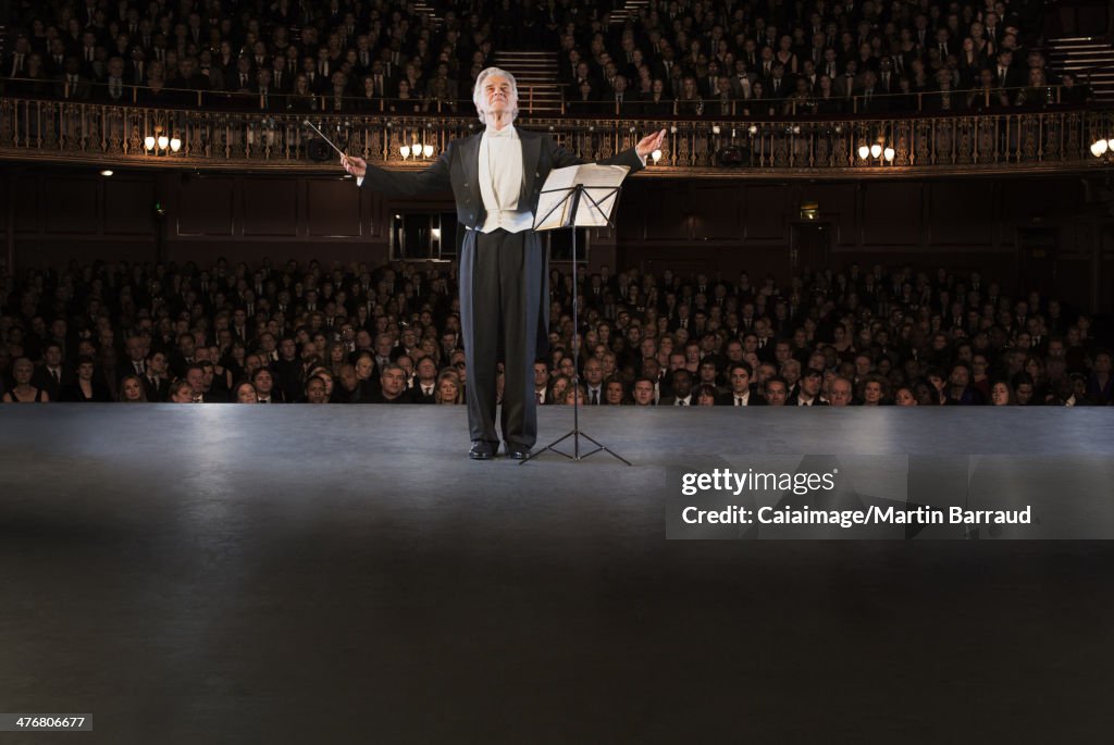 Conductor performing on stage in theater