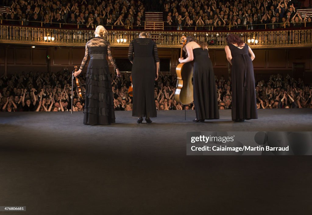 Quartet bowing on stage in theater