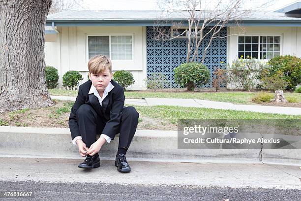 boy in suit sitting on suburban street - boy tying shoes stock pictures, royalty-free photos & images