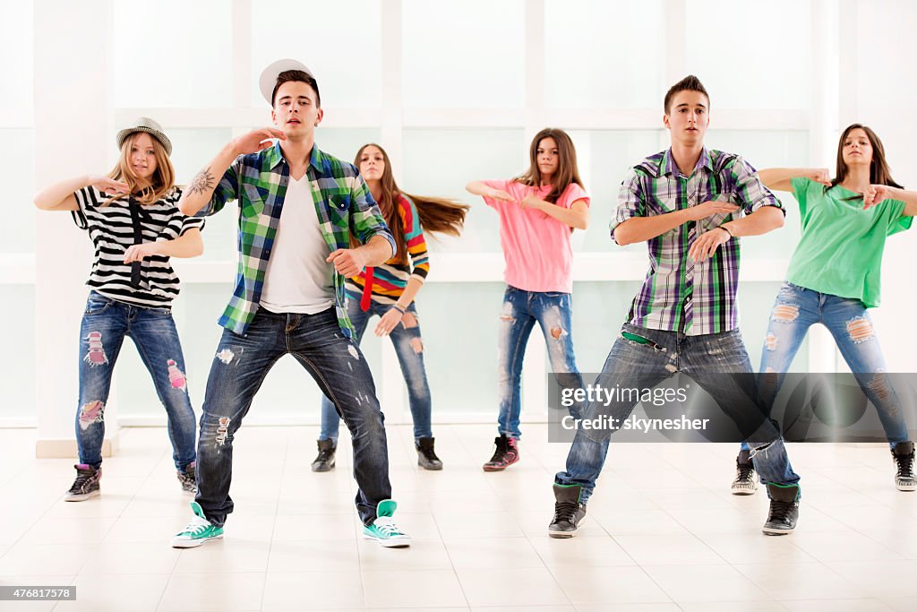 Team of teenage dancers exercising hip hop dance.