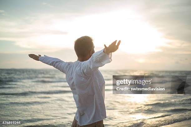 tifo uomo le braccia aperte al tramonto sul mare - arms open foto e immagini stock