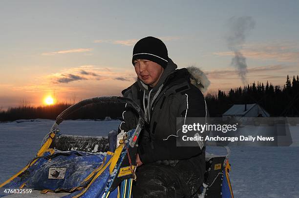 Musher Mike Williams Jr. Sits on his dog sled as he changes batteries in his headlamp at the Nikolai checkpoint during the Iditarod Trail Sled Dog...