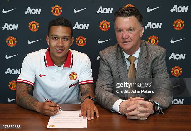 Manchester United's new signing Memphis Depay signs his contract in the presence of his new manager Louis Van Gaal at the Aon Training Complex on...