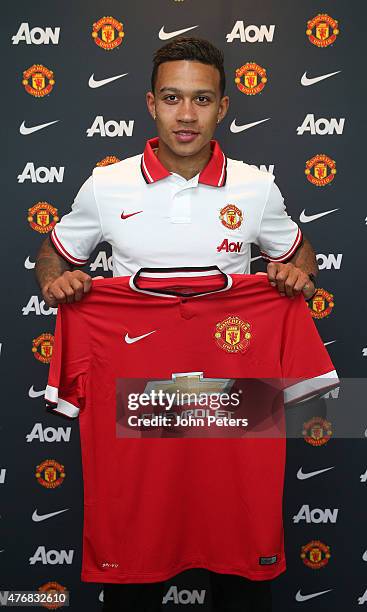 Manchester United's new signing Memphis Depay poses with his new shirt following the completion of his transfer at the Aon Training Complex on June...