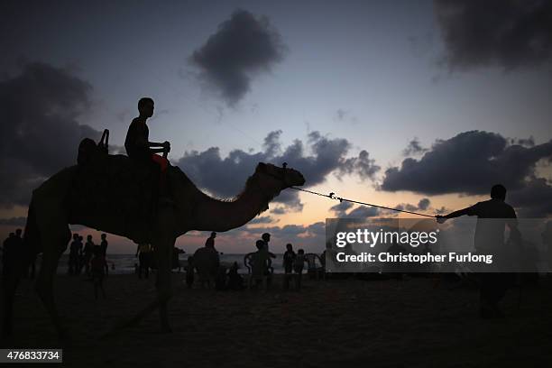 Young boy enjoys a camel ride as Palestinians relax and spend leisure time on Gaza Beach on June 11 Gaza City, Gaza. The devastation across Gaza can...