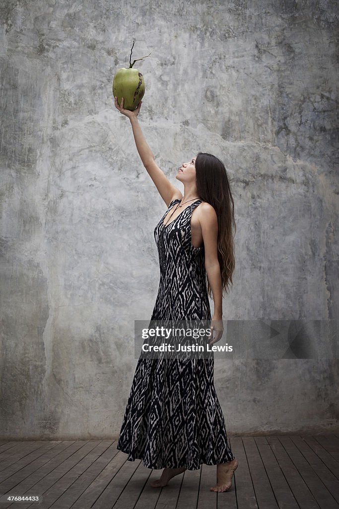 Girl in long dress holding and looking at coconut