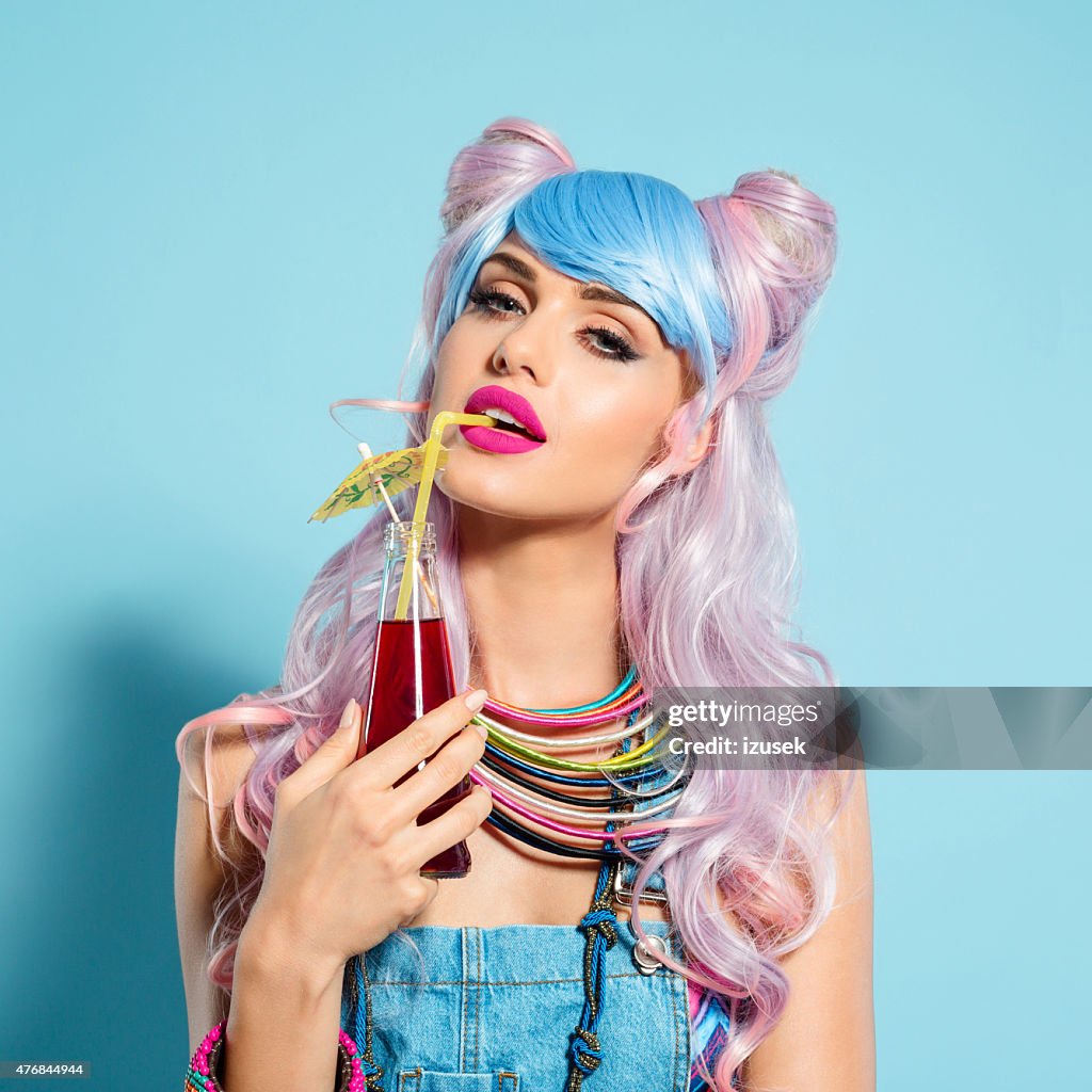 Blue-pink hair girl in funky manga outfit holding summer cocktail