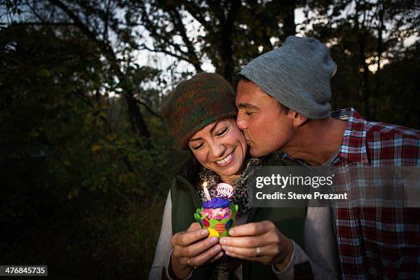 mature couple outside tent holding birthday cupcake - holding birthday cake stock pictures, royalty-free photos & images