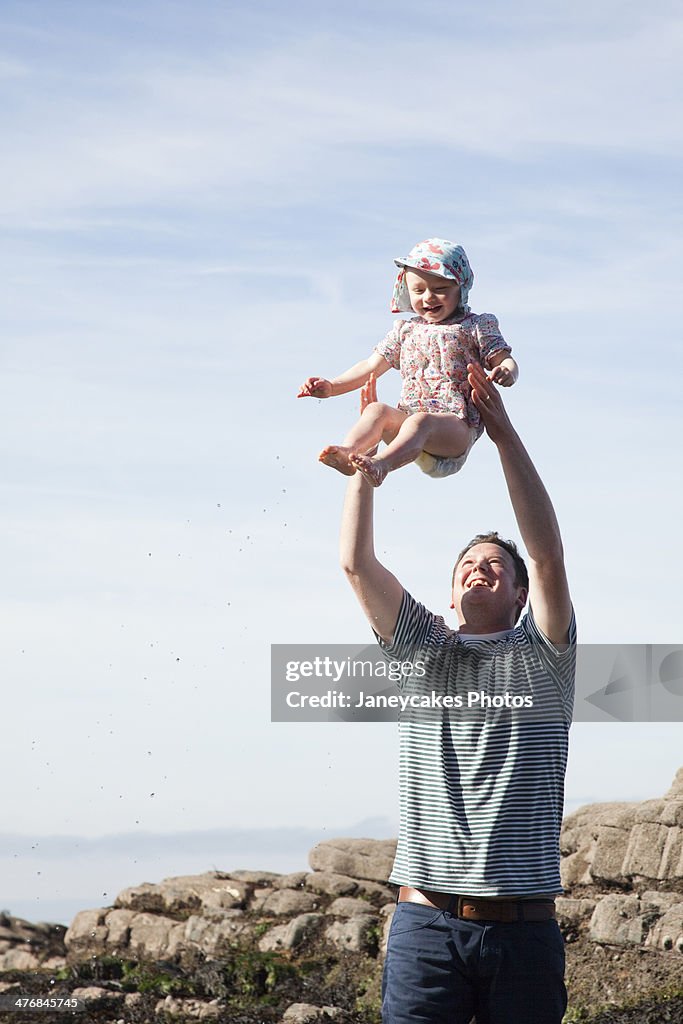 Father throwing child in air on beach