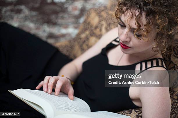 portrait of young woman reclining and reading book - ashley grace stock pictures, royalty-free photos & images