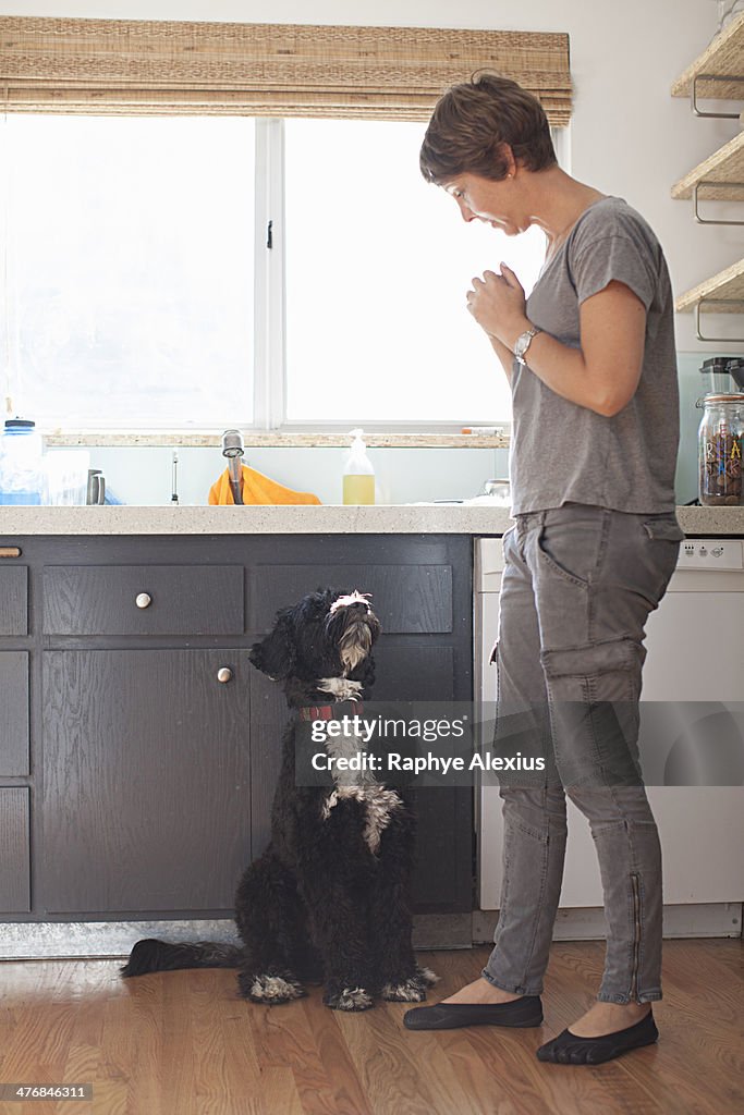 Mature woman and her pet dog in kitchen