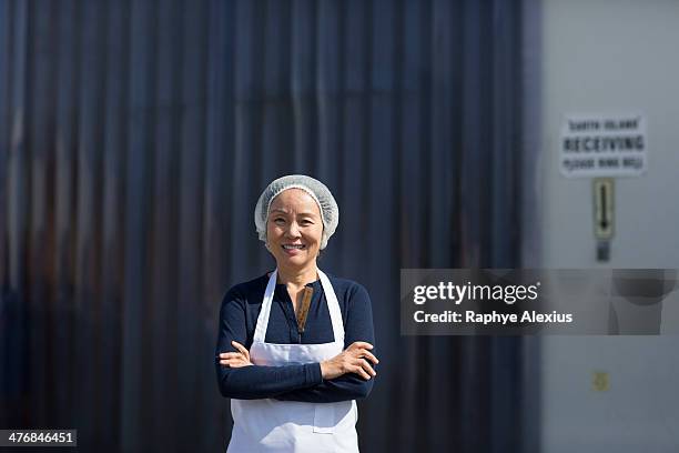 portrait of female factory worker, arms folded - haarnet stockfoto's en -beelden