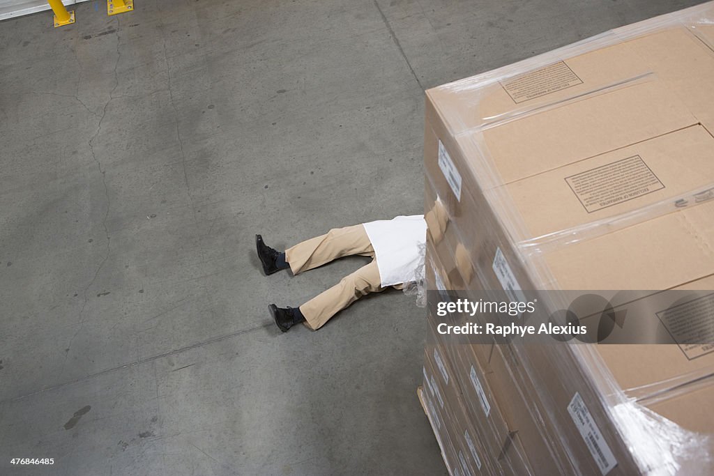 Man lying on floor with cardboard boxes in warehouse