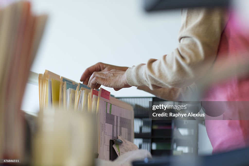 Senior woman looking through filing cabinet