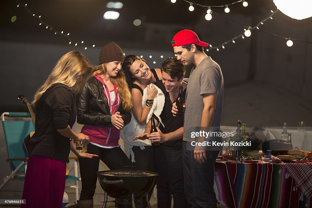 Young adult friends keeping warm at rooftop party