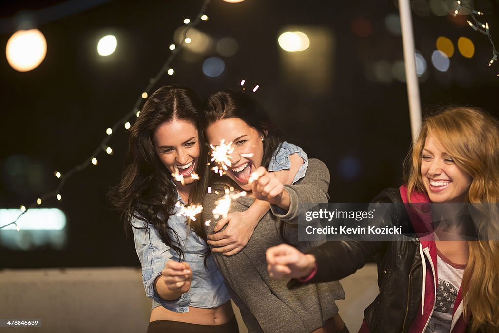 Female friends with sparklers at rooftop party