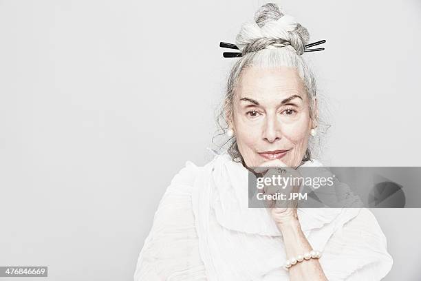 studio portrait of sophisticated senior woman with hand on chin - coole oma stock-fotos und bilder