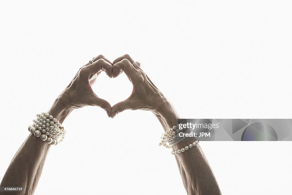 Studio shot of mature woman's hands making heart shape