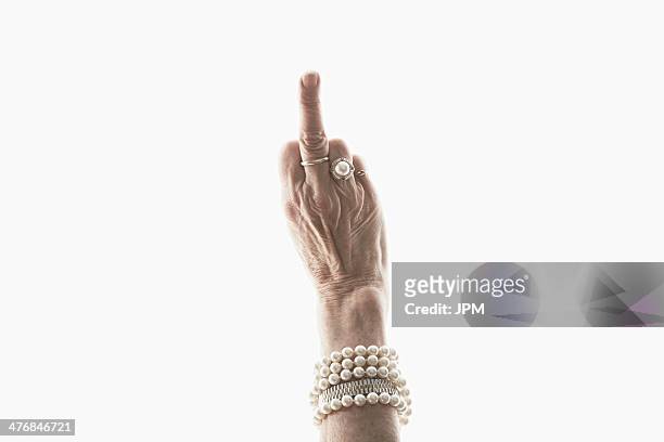 studio shot of mature woman's hand making obscene gesture - hand gag foto e immagini stock
