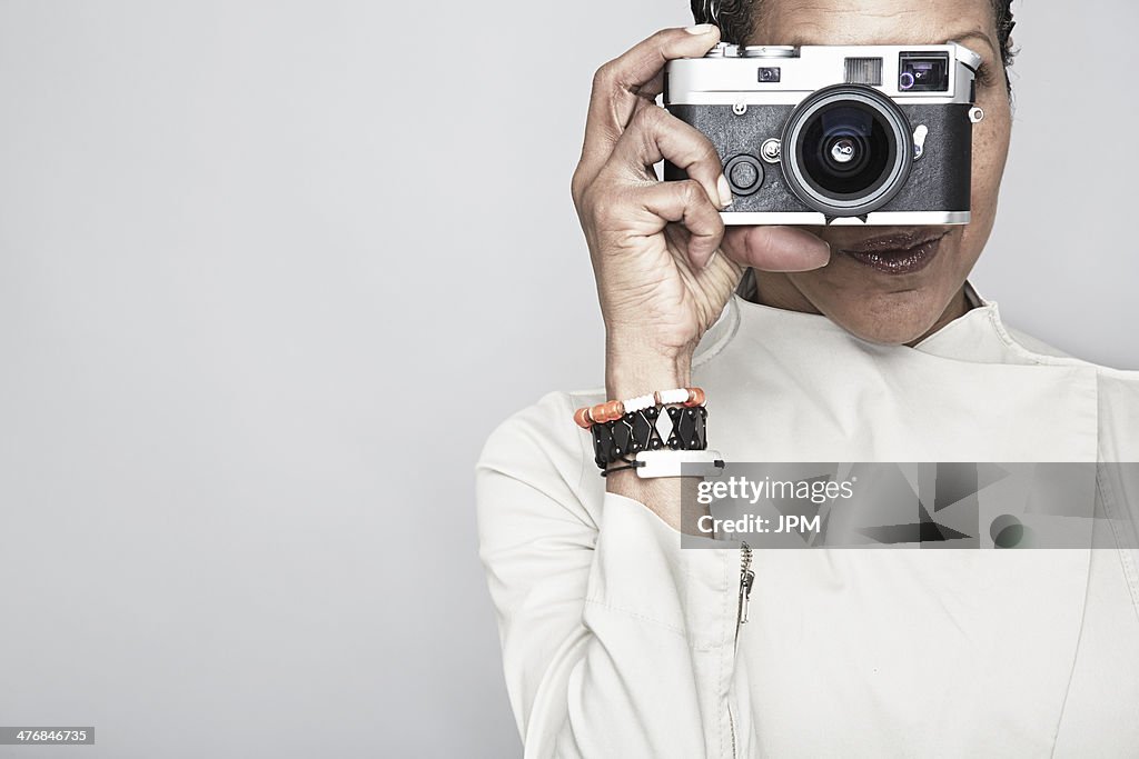 Studio portrait of mature woman holding up camera