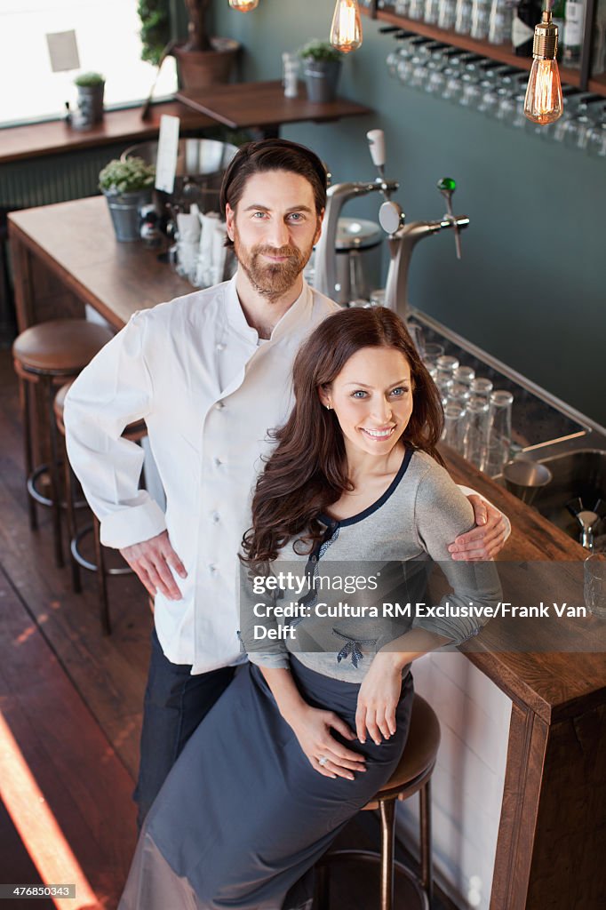 Chef with arm around woman at bar