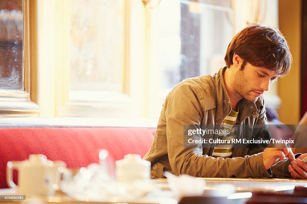 Mid adult man using mobile in cafe