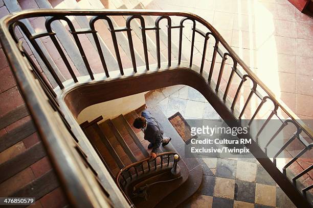 mid adult man climbing lobby stairs - salire le scale foto e immagini stock