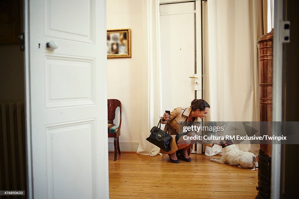 Young woman petting dog on return to apartment