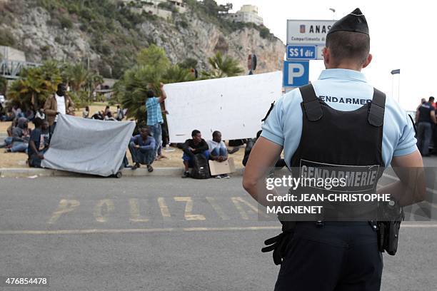French Gendarme stands guard on the French side of the French-Italian border in Menton, as migrants hoping to cross wait on the Italian side in the...