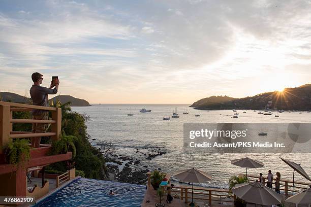 man takes pic with digital tablet above lagoon - ixtapa stock pictures, royalty-free photos & images