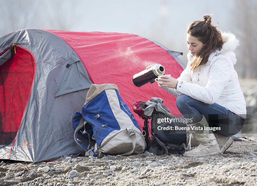 Woman pouring hot tea in a campsite