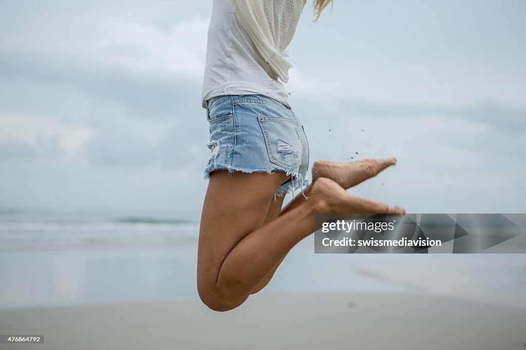 Woman jumping at the beach for positive emotion