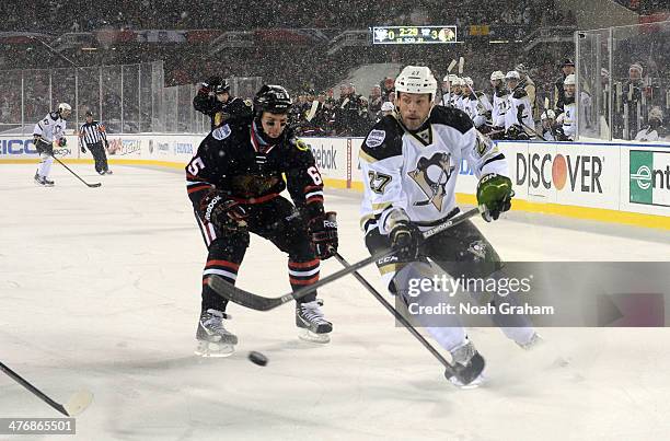 Craig Adams of the Pittsburgh Penguins tries for a backhand shot past Andrew Shaw of the Chicago Blackhawks during the 2014 NHL Stadium Series game...