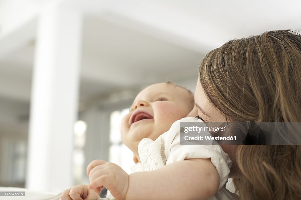 Mother kissing her laughing baby girl