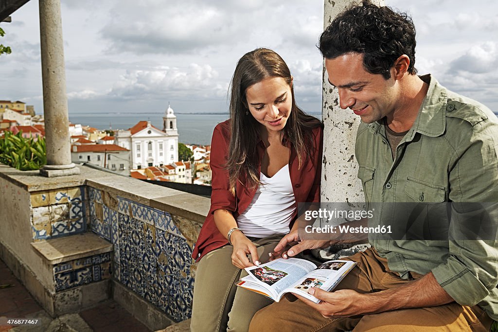 Portugal, Lisboa, Alfama, Miradouro de Santa Luzia, young couple with guidebook