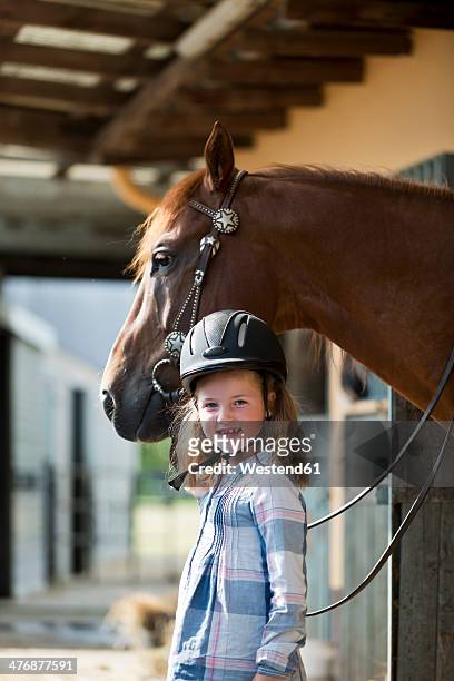germany, nrw, korchenbroich, little girl with horse in stable - equestrian helmet stock-fotos und bilder