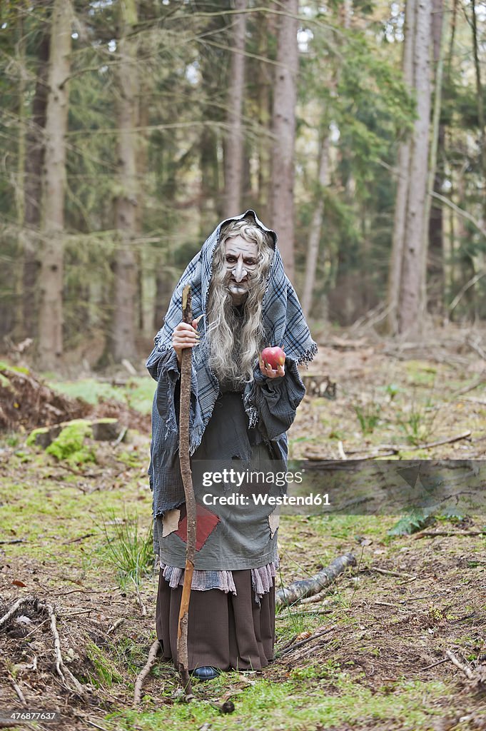 Germany, North Rhine-Westphalia, Moenchengladbach, Scene from fairy tale, witch holding an apple in the woods